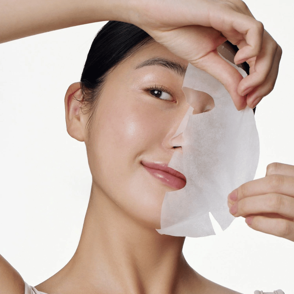 Dette billede viser en person, der bruger en ansigtsmaske, specifikt "Galactomyces Glutathione Daily Mask" fra Some By Mi. Masken lysner huden og giver en strålende glød, samtidig med at den plejer og fugter huden i dybden, takket være ingredienser som glutation og vitamin C.
