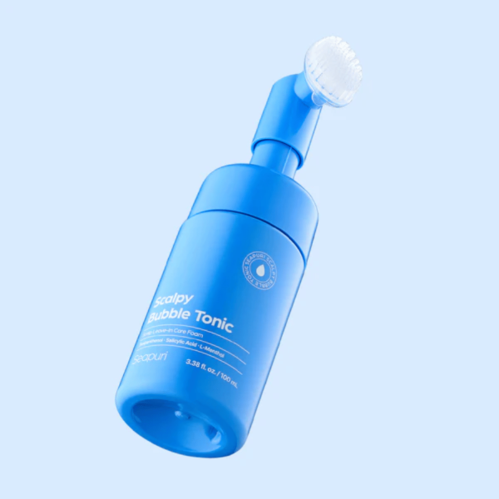 Stilrent produktbillede af Seapuri Scalpy Bubble Tonic mod lyseblå baggrund, som fremhæver det moderne design og det unikke børstehoved til hovedbundspleje.