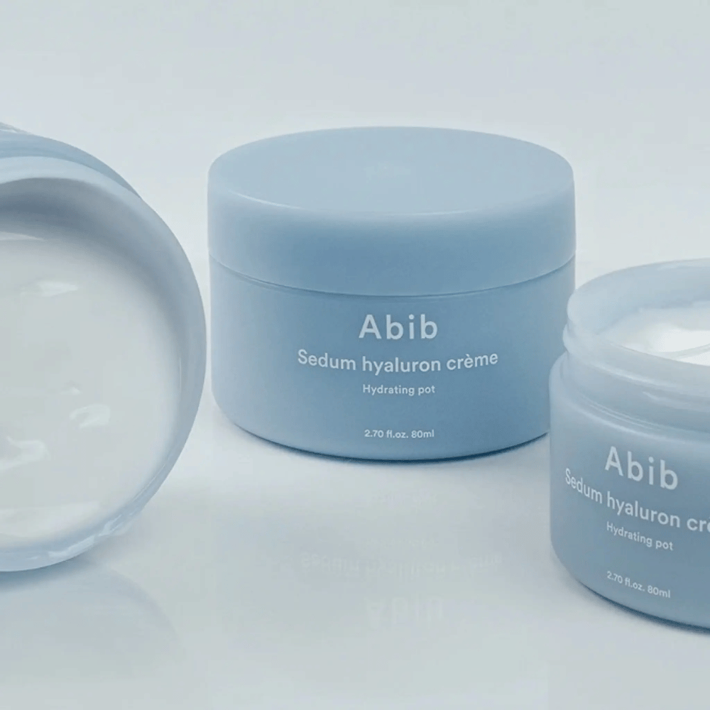 Tre krukker af Abib Sedum Hyaluron Crème Hydrating Pot 80 ml i lyseblå minimalistisk design, hvoraf en åben krukke viser den cremede hvide konsistens.