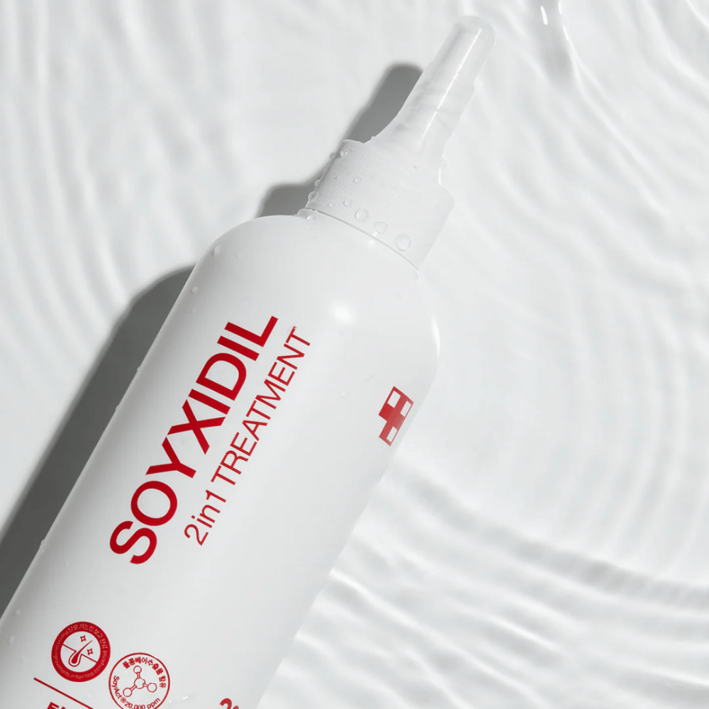 Flaske af Medicube Soyxidil 2in1 Treatment ligger på bølgende vandoverflade, hvilket symboliserer fugtgivende og opfriskende pleje.