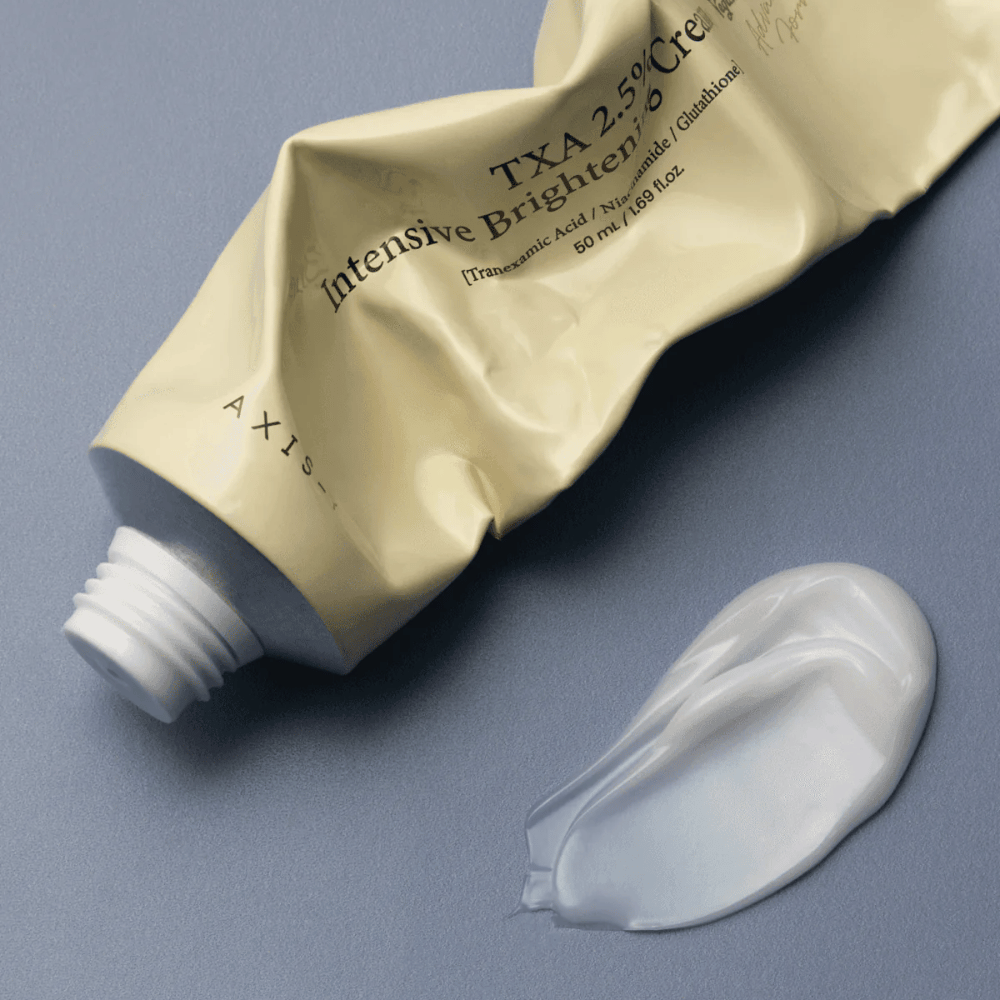Produktbillede med tuben og en klat creme ved siden af for at vise den bløde, cremede konsistens og fugtgivende formel. Fokus er på glow og jævn påføring.