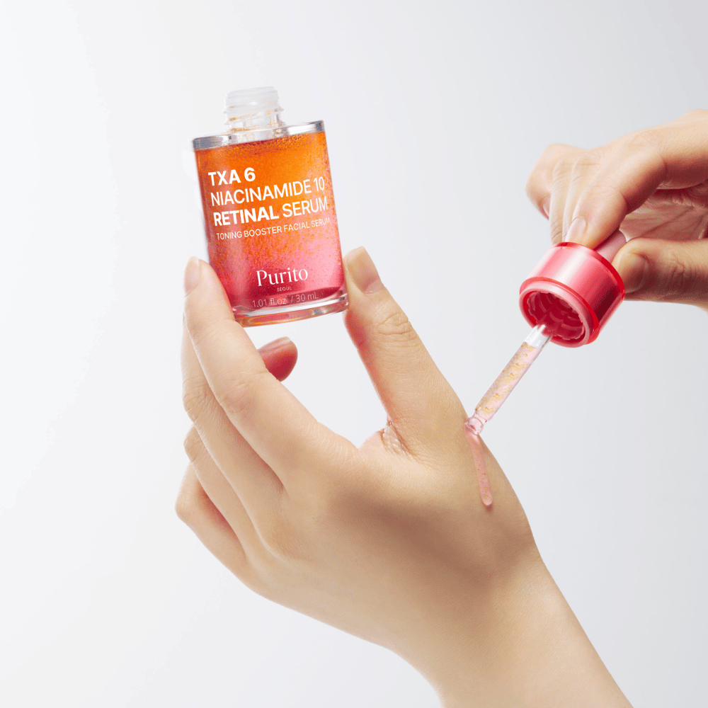 Hånd påfører Purito TXA 6 Niacinamide 10 Retinal Serum. Let formel med aktive ingredienser for glød, elasticitet og klarere hud.