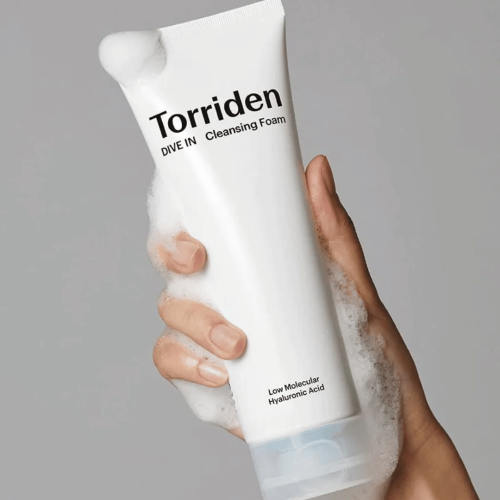 En hånd der holder en tube pH-balanceret Torriden DIVE-IN Low Molecular Hyaluronic Acid Cleansing Foam 150ml.