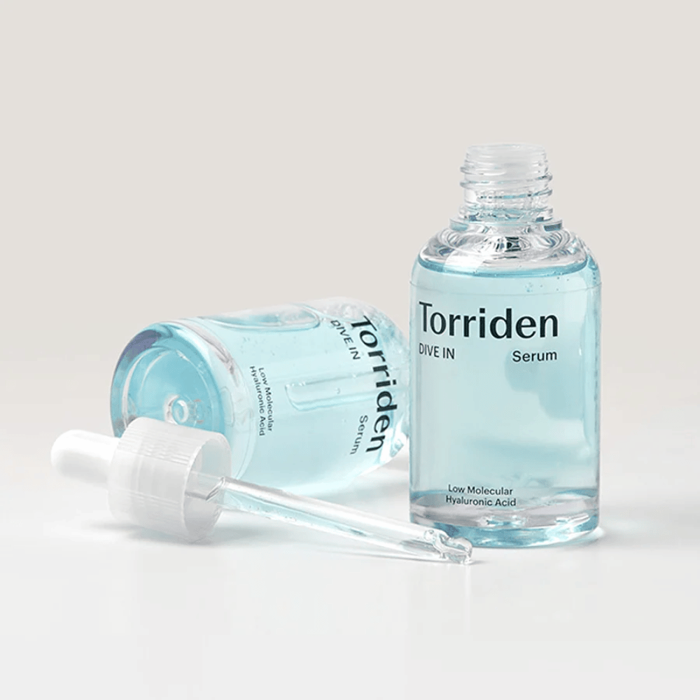 En flaske Torridens DIVE-IN Low Molecule Hyaluronic Acid Serum 50ml ved siden af en flaske vand, som fremhæver hyaluronsyreserum og fugtgivning.