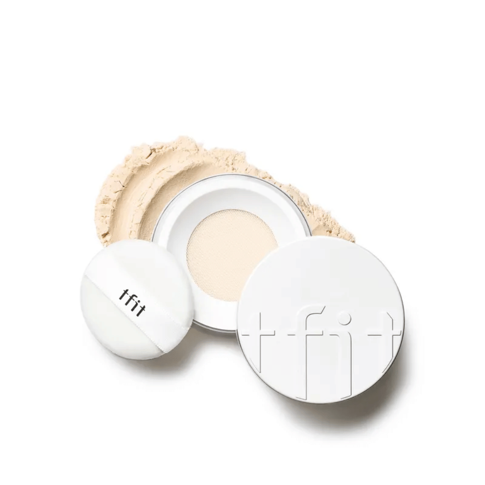Åben dåse med TFIT Translucent Set Finishing Powder i nuancen Skin Beige, med medfølgende puff og setting powder spredt rundt omkring.