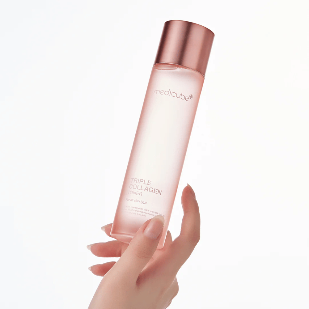 Hånd der holder i en lyserød flaske af Medicube Triple Collagen Toner 4.0, en fugtgivende og opstrammende toner til alle hudtyper.