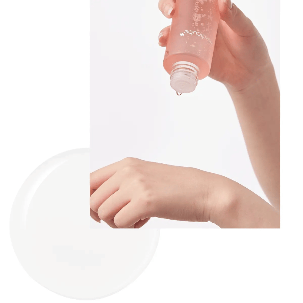 Hånd der hælder Medicube Triple Collagen Toner 4.0 fra en lyserød flaske på huden, viser den fugtgivende konsistens.