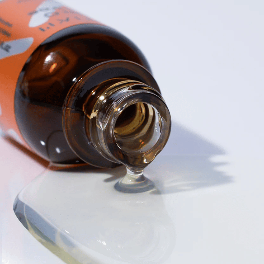 Nærbillede af TIA'M Vita C Source-serum, der løber fra en brun glasflaske. Serumets klare formel fremhæver dets koncentrerede C-vitaminindhold for en strålende hud.