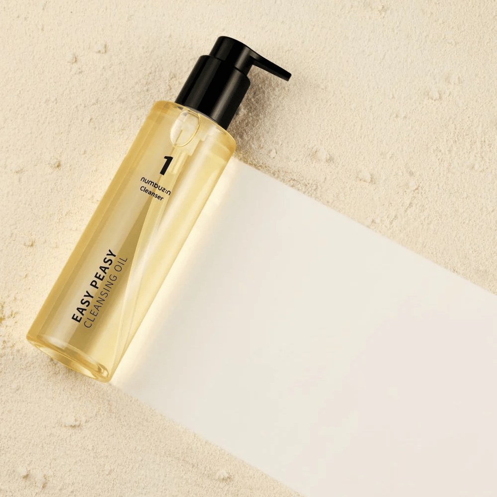 Numbuzin No.1 Easy Peasy Cleansing Oil liggende på sandfarvet overflade med skygge.