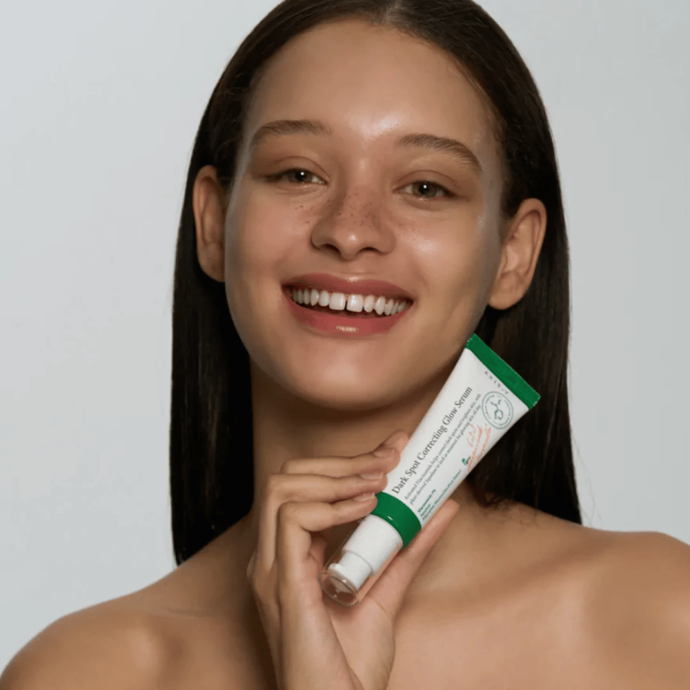 En ung kvinde holder en tube med AXIS - Y Dark Spot Correcting Glow Serum 50ml.