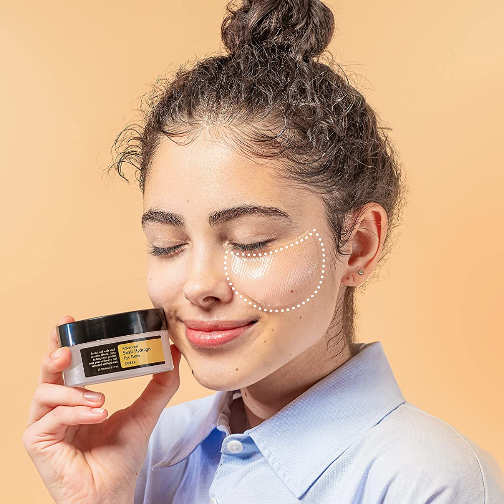 En kvinde der holder en krukke COSRX Advanced Snail Hydrogel Eye Patch 60 stk ansigtscreme.