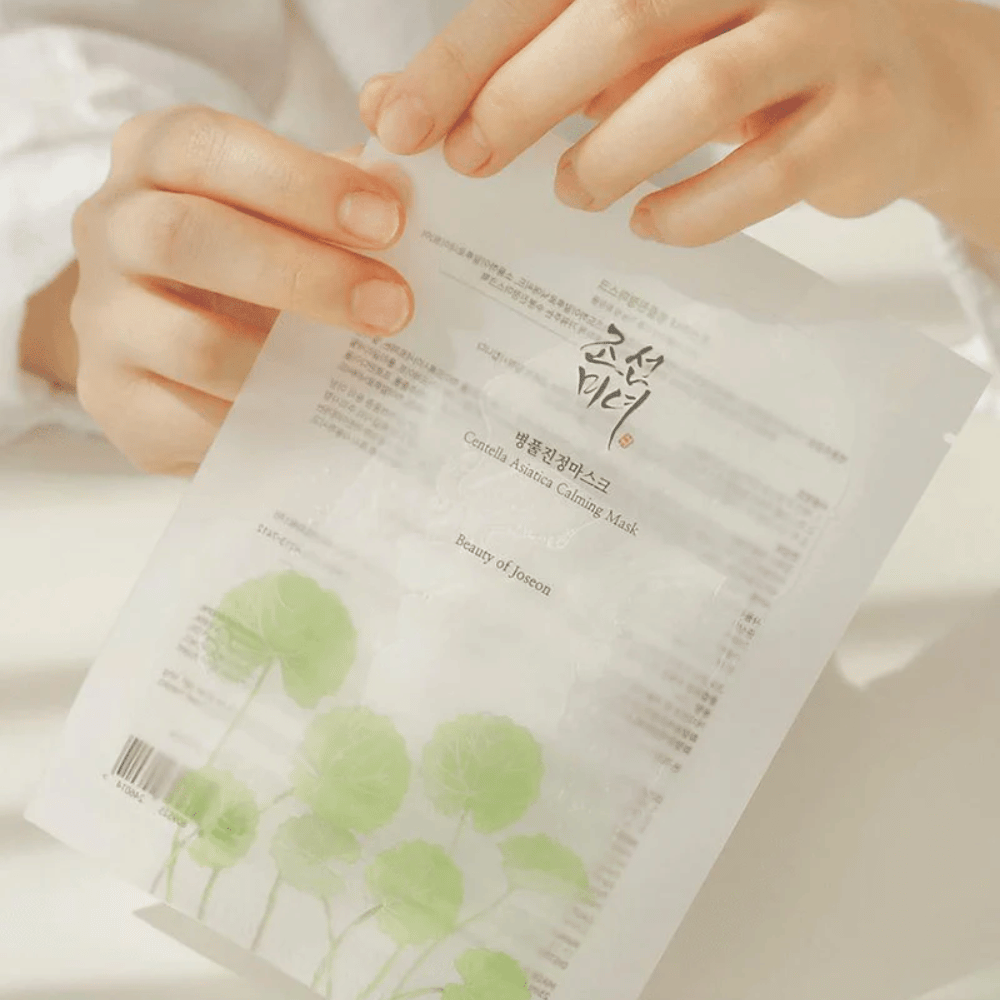 En person som holder op et ark papir med en Beauty of Joseon Centella Asiatica Calming Mask 1 stk på.