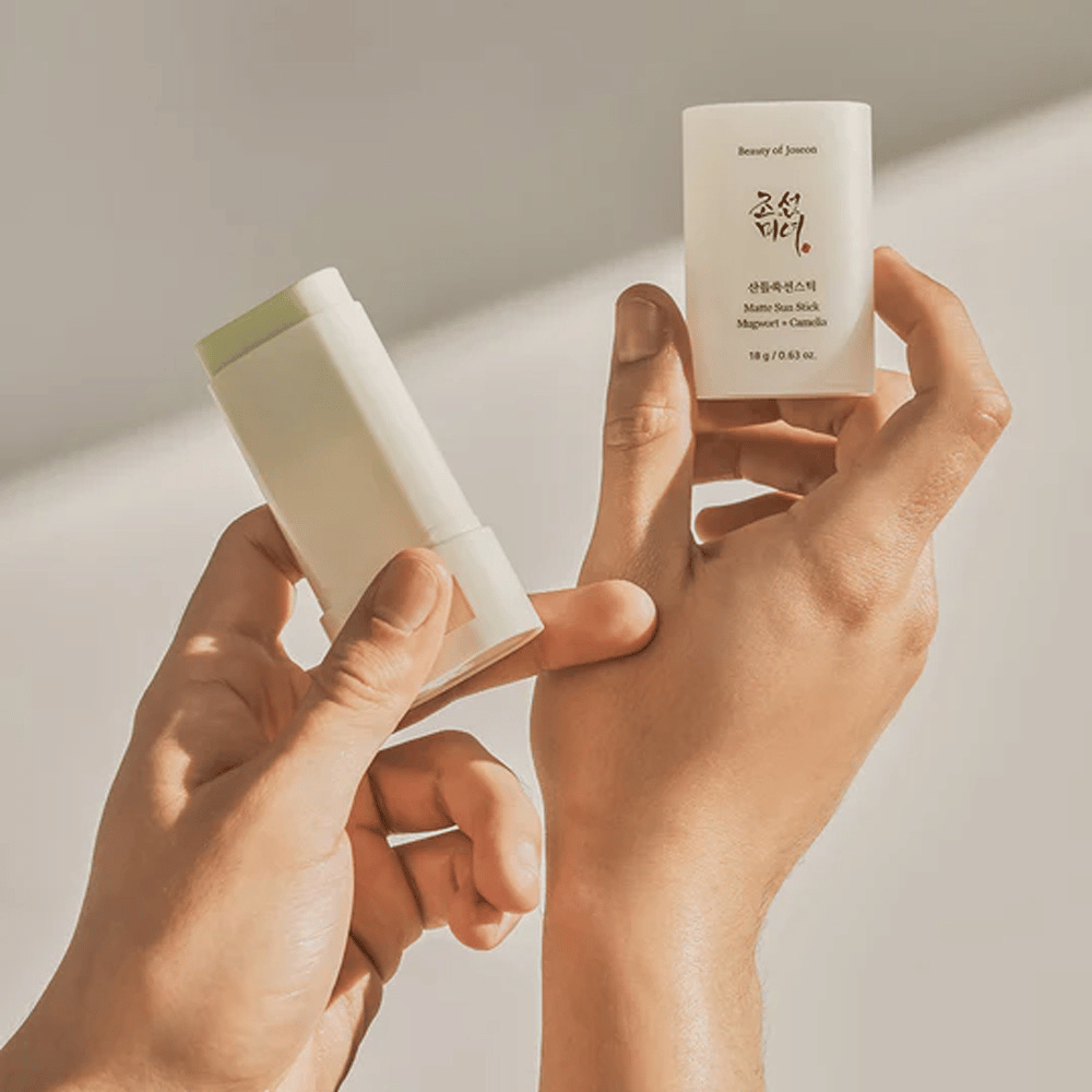To hænder der holder en stift af Beauty of Joseon's Matte Sun Stick 18g SPF50 PA++++.