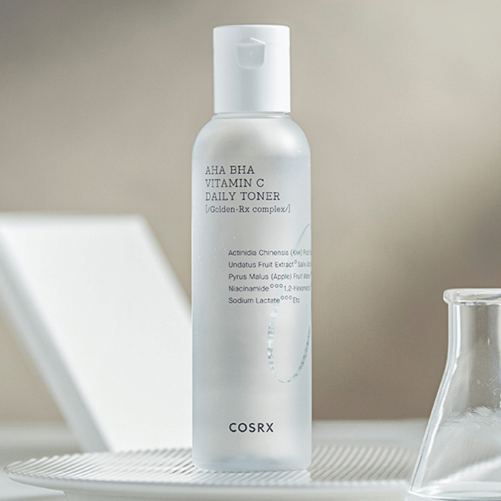 En flaske COSRX Refresh AHA BHA Vitamin C Daily Toner 150ml som sidder ovenpå en hvid plade.