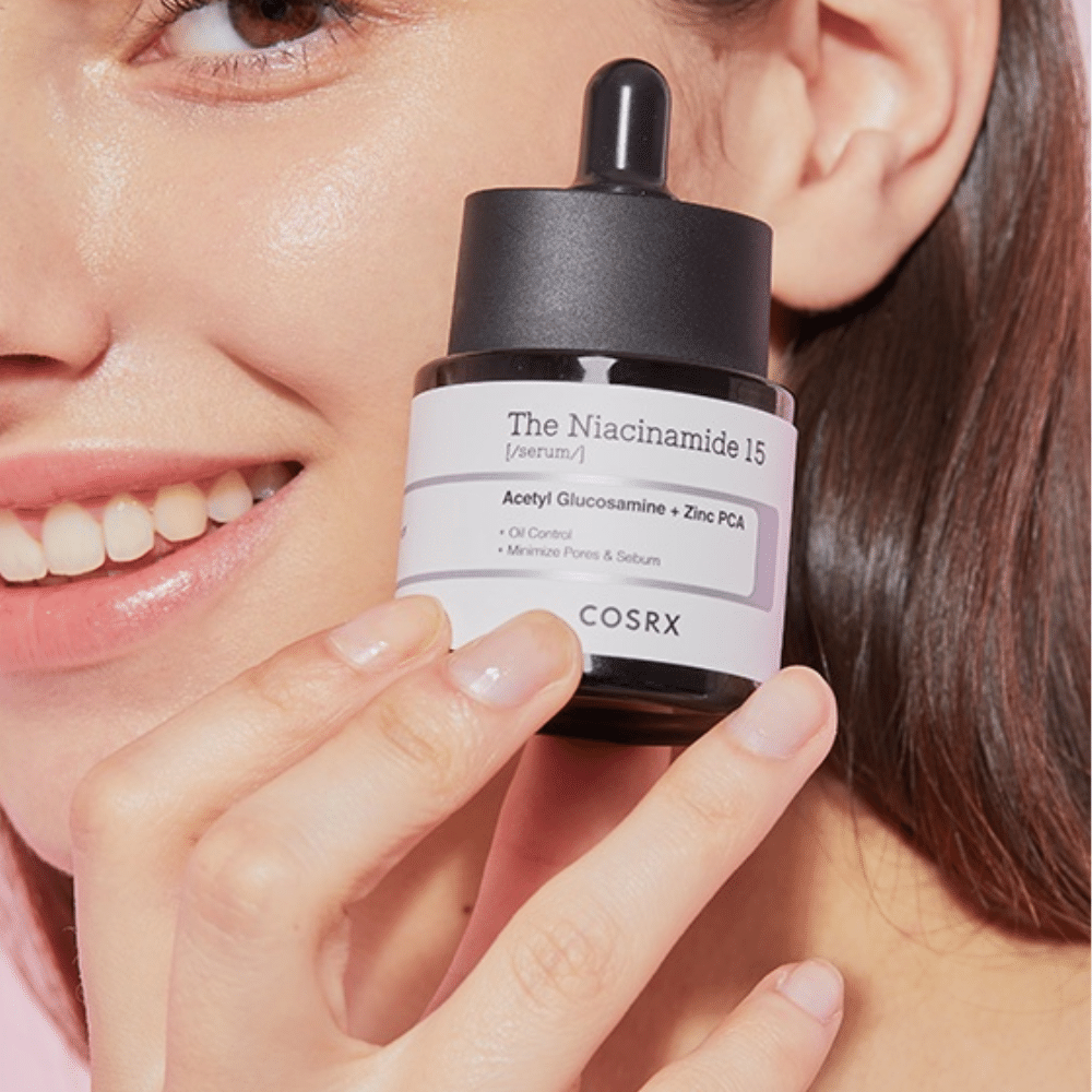 En kvinde holder en flaske af COSRX Niacinamid 15 Serum 20ml for niacinamid og talgproduktionen.
