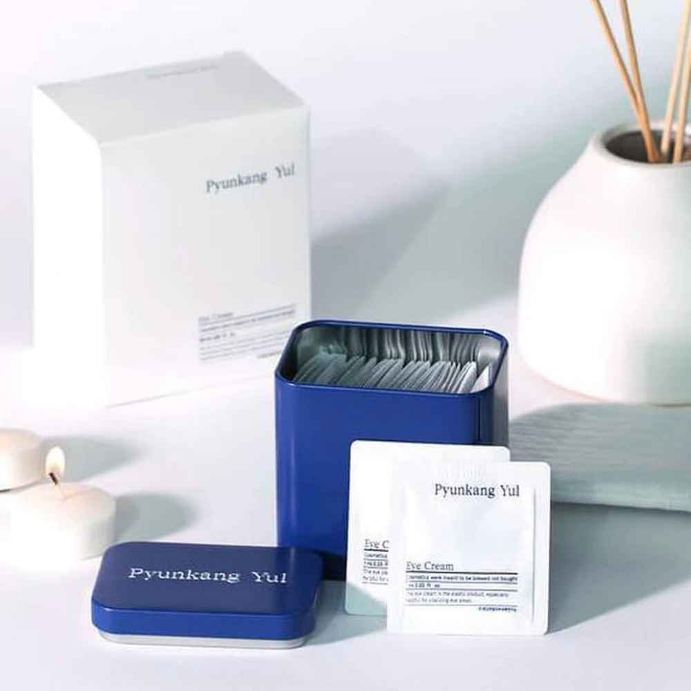 En hvid æske med blåt låg og Pyunkang Yul Eye Cream 1ml x 50stk ved siden af.