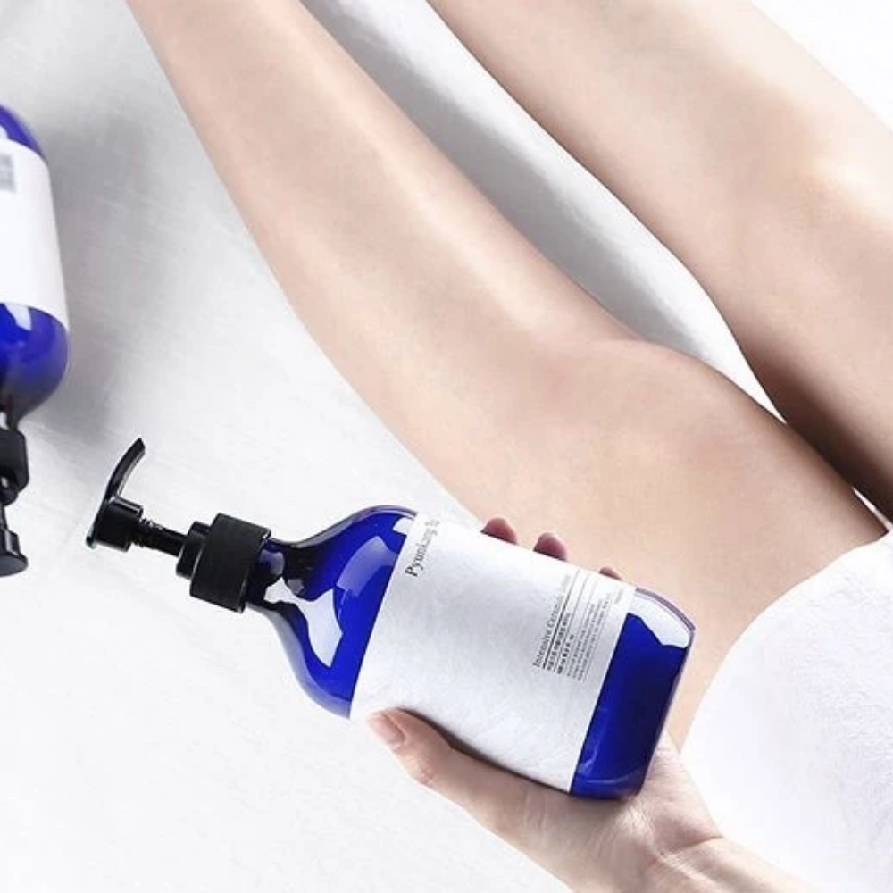 En kvinde der holder en flaske Pyunkang Yul Intensive Ceramide Lotion 500ml ved siden af sine ben.