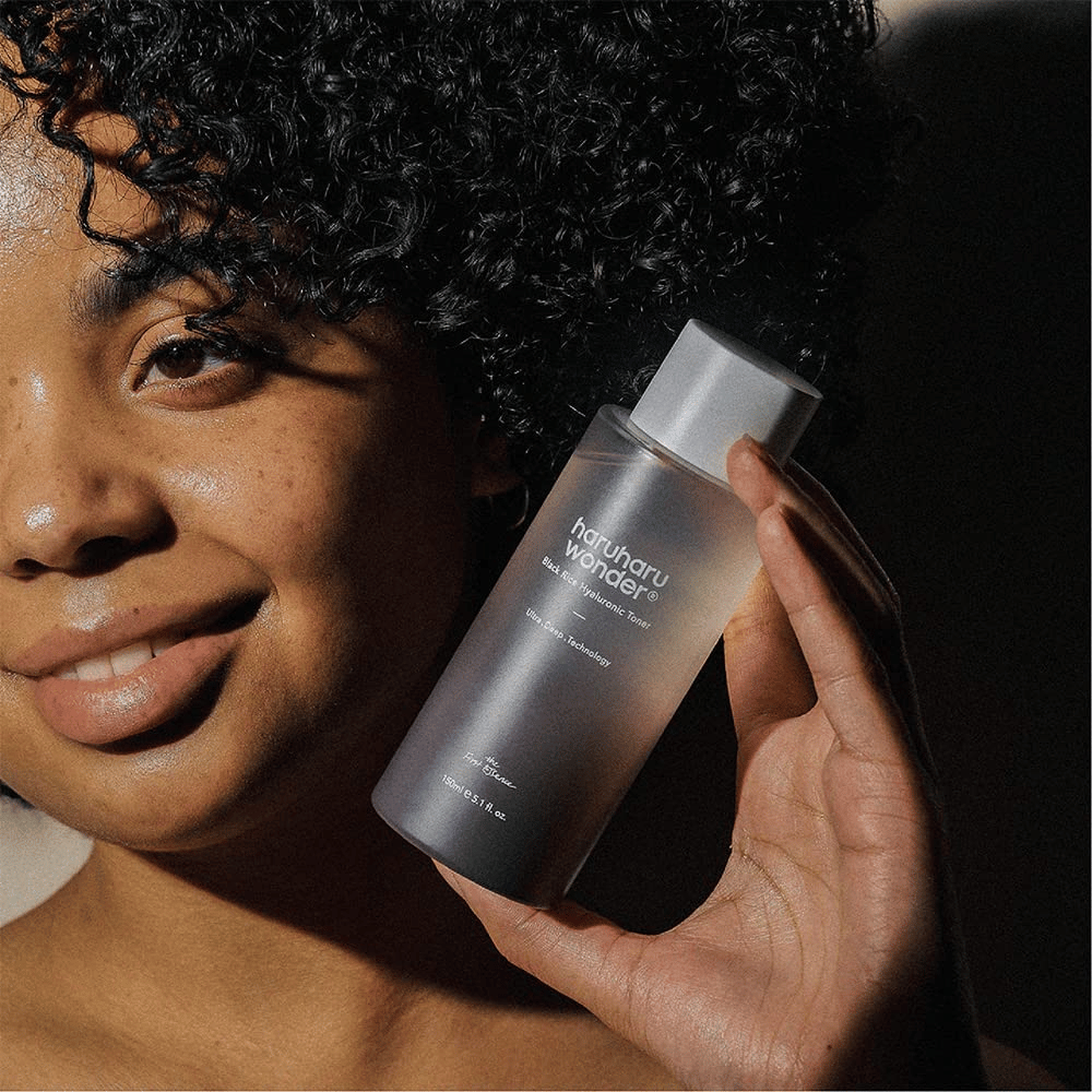 En kvinde der holder en flaske Haruharu Wonder Black Rice Hyaluronic Toner Original 150ml.