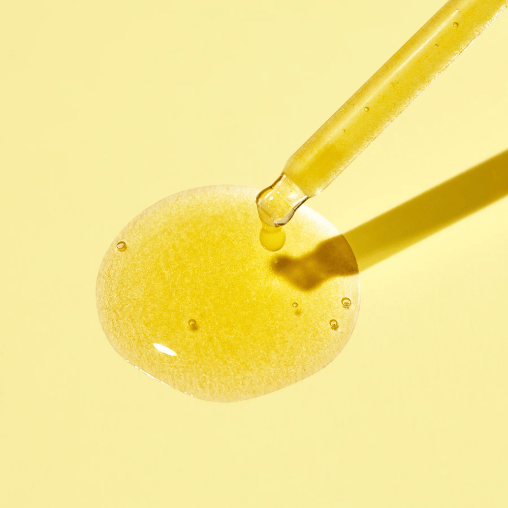 En dråbe væske på en gul baggrund, med MISSHAs Vita C Plus Spot Correcting & Firming Ampoule.